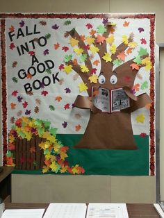 a bulletin board decorated with fall leaves and a paper cutout of a tree reading a book