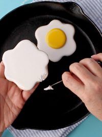 a person holding an egg on a plate with two fried eggs in the shape of hashbrowns