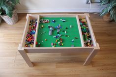 a table made out of legos on top of a hard wood floor next to a potted plant