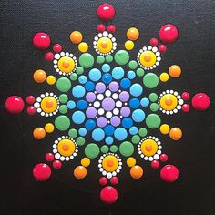 a colorful design on a black surface with circles and dots in the shape of a snowflake