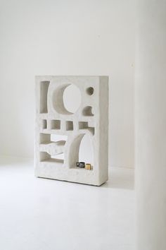 a small white sculpture sitting on top of a white table next to a wall mounted phone