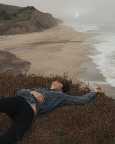 a woman laying on the ground next to an ocean