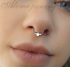 a woman wearing a nose ring with a blue opal stone on it's side