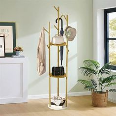 a coat rack with hats and umbrellas on it next to a potted plant