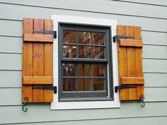 an open window with wooden shutters on the side of a house