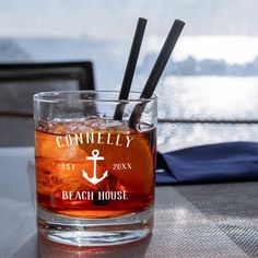 a close up of a drink in a glass on a table near the water with two straws sticking out of it