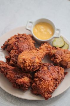 fried chicken on a plate with dipping sauce and cucumber next to the bowl