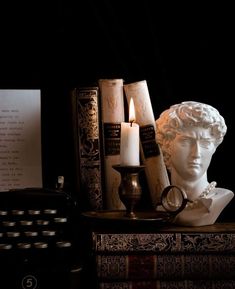 a white busturine sitting on top of a table next to books and candles