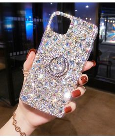 a woman holding up her phone case with jewels on it