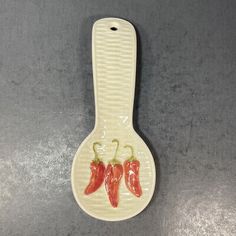 a ceramic spoon with three chili peppers on it