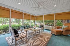 a living room filled with furniture and windows covered in shades on top of blue carpeted flooring