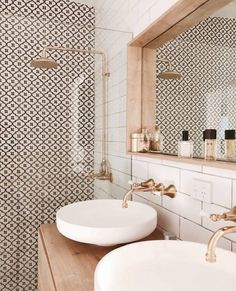 two white sinks sitting under a mirror in a bathroom next to a wooden counter top