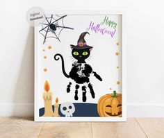 a black cat wearing a witches hat and sitting in front of halloween decorations