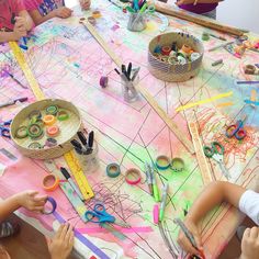 children are sitting at a table making art