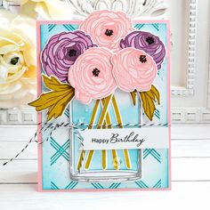 a close up of a card with flowers on it and a vase in the background