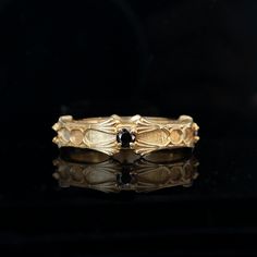 a close up of a gold ring on a black surface with reflections in the background