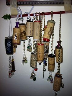 there are many wine corks hanging on the wall with chains and charms attached to them