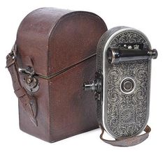 two old fashioned cameras sitting next to each other on a white background, one is brown and the other is silver