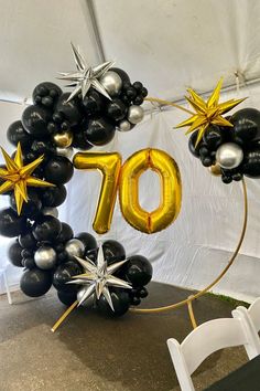 a balloon arch with the number seventy on it and stars hanging from it's sides