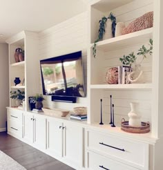 a living room filled with white furniture and lots of shelves on top of it's sides