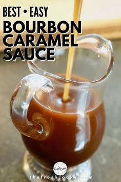 the best and easy bourbon caramel sauce in a glass pitcher with a wooden stick sticking out of it