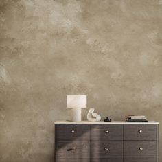 a dresser with a lamp on top of it next to a wall that has been painted beige