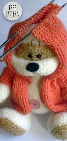 a knitted teddy bear with a scarf on it's head and needles in its mouth