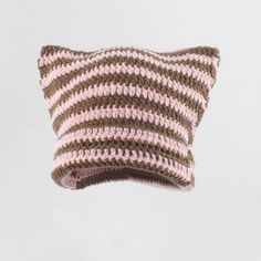 a pink and brown striped knitted pillow hanging from a hook on a white wall