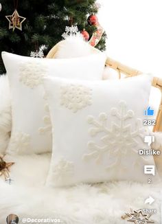 two white pillows with snowflakes on them next to a christmas tree and decorations