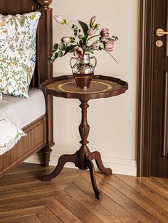 a small table with flowers on it in a room next to a bed and door