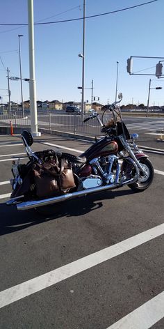 a motorcycle parked in a parking lot with bags on the back seat and luggage strapped to it