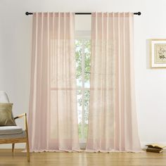 a living room with a chair and pink curtains