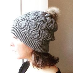 a woman wearing a gray knitted hat with a pom - pom