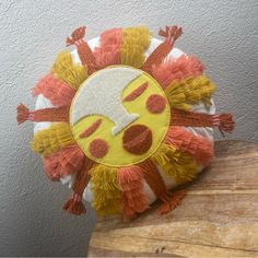 a yellow and orange decorative pillow on top of a wooden table next to a gray wall