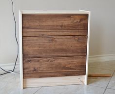 a wooden box sitting on the floor next to an electrical cord and plugged in