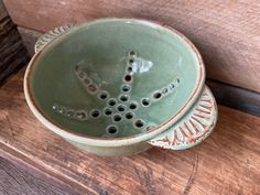 two green bowls sitting on top of a wooden table next to each other with holes in them