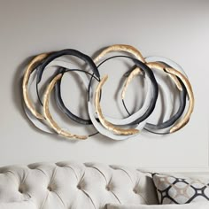 a white couch sitting next to a wall mounted with four circular metal rings on it