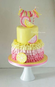 a yellow cake with pink and yellow ruffles, lemon slices, and ribbons