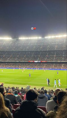 a stadium filled with lots of people watching a soccer game on a big field at night