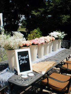 an outdoor table with flowers and a sign on it