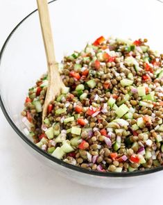 a glass bowl filled with lentils, cucumber and red onion salad dressing