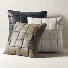 two pillows sitting next to each other on top of a white floor covered in leather