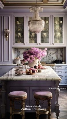 a kitchen with an island, chandelier and flowers in the middle of it