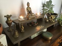 a shelf with candles, statues and other items on it in a living room area