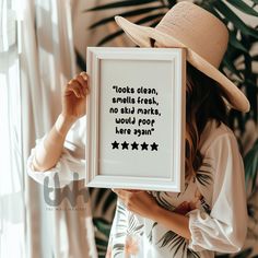 a woman wearing a hat holding up a framed poster with the words'dots clean, smells fresh, no ski marks, would poop here again '