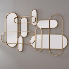 three mirrors mounted to the side of a wall next to each other with different shapes and sizes