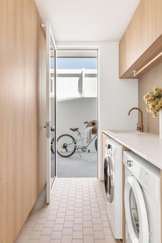 a washer and dryer in a small room with wooden cabinets, tile flooring and white walls