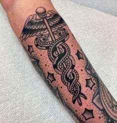 a black and white photo of a tattoo on someone's arm with a medical symbol