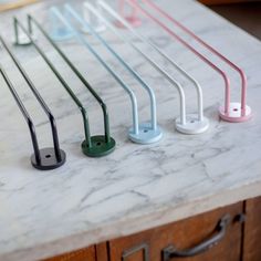 four different colored handles on a marble counter top with drawers in the backround