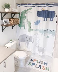 a bathroom with a shower curtain that has animals on it and the word splash written in multicolored letters